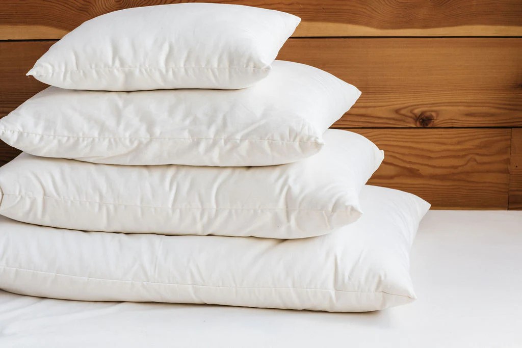 A stack of four holy lamb organics wool-filled pillows
