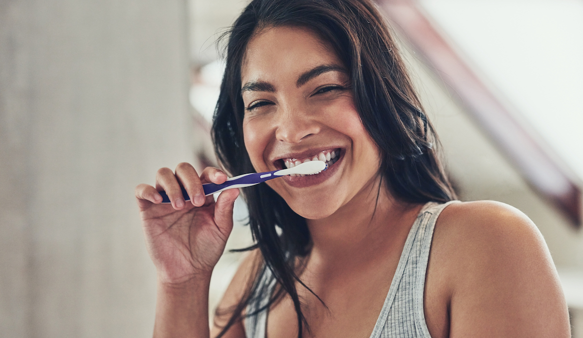 a woman brushing her teeth with one of the best soft toothbrushes