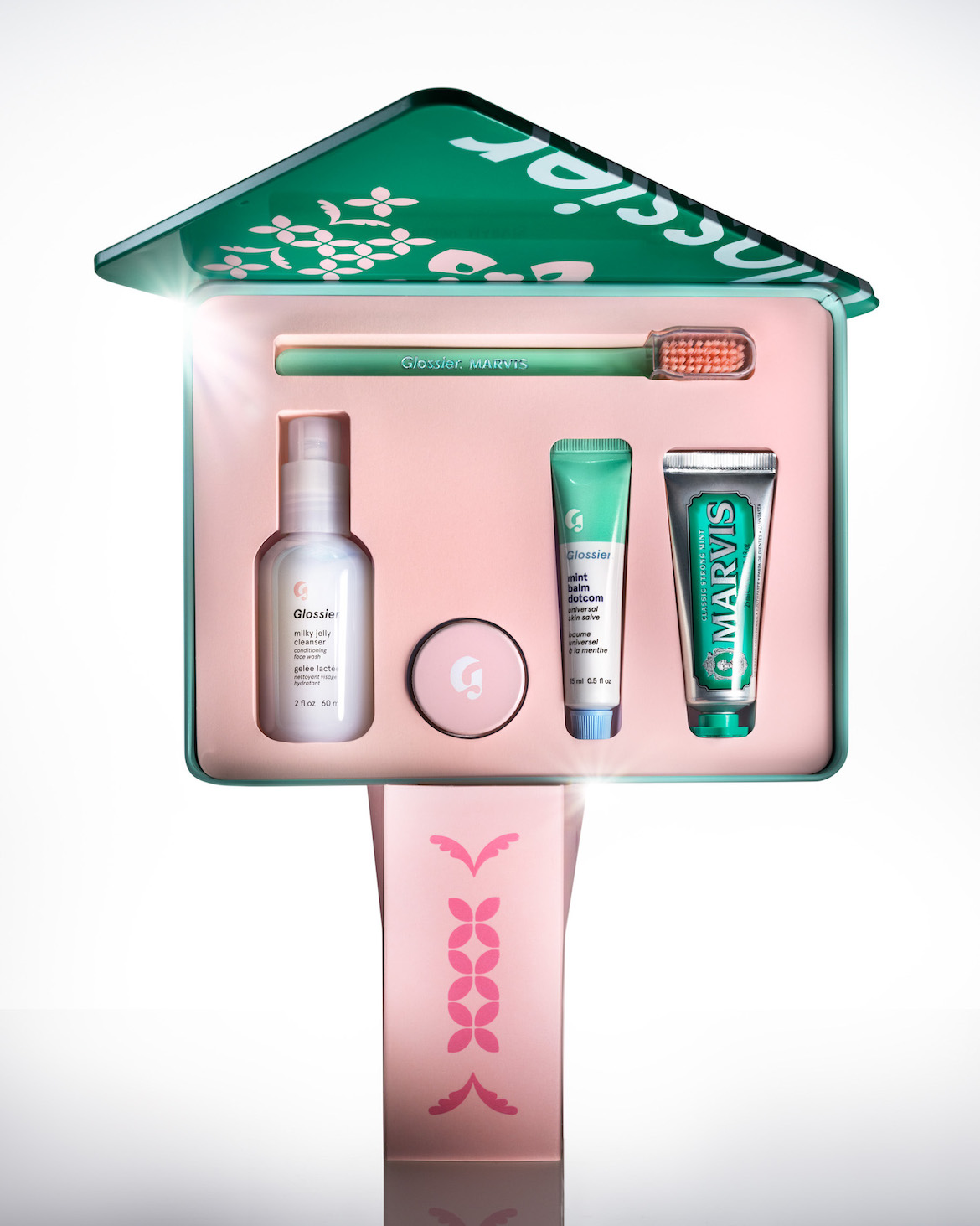 glossier cross country gift set in reusable tin balancing on another glossier gift set box