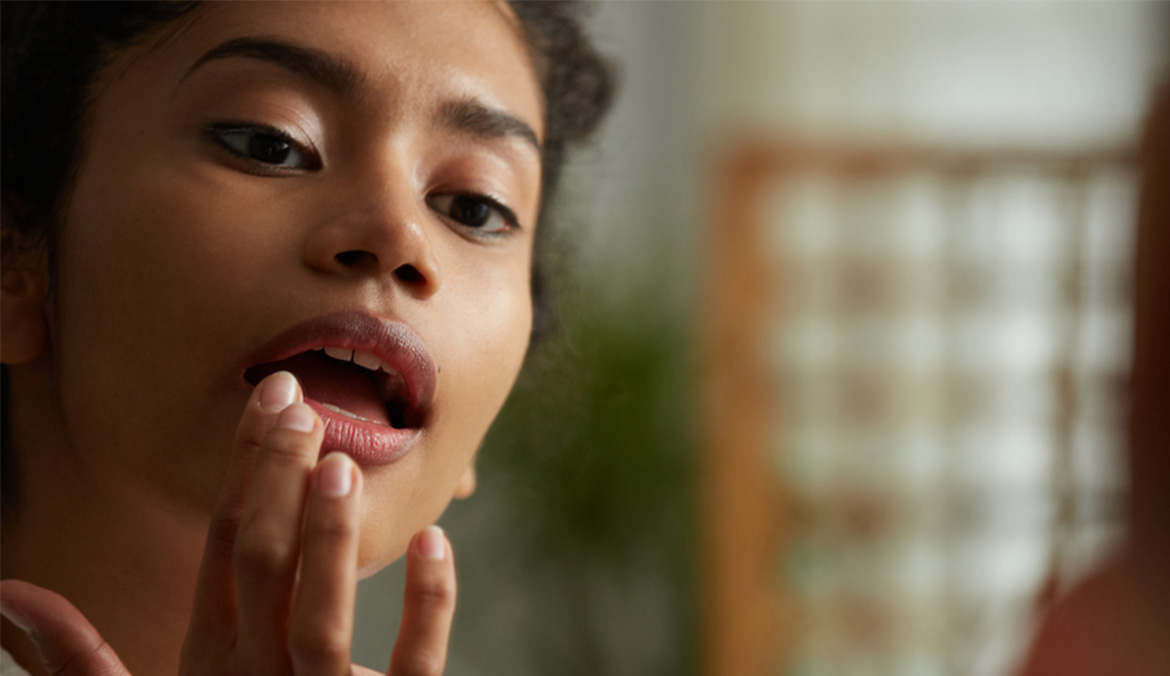 A close up of a woman applying lip balm.