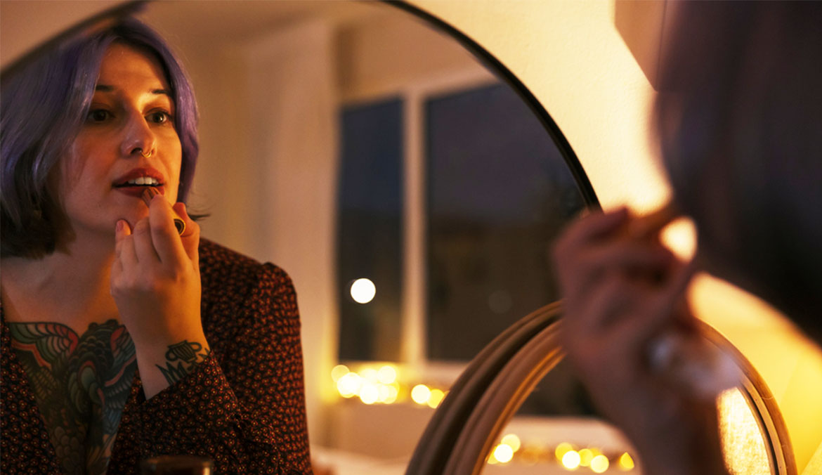 A woman applying lipstick before a holiday party.