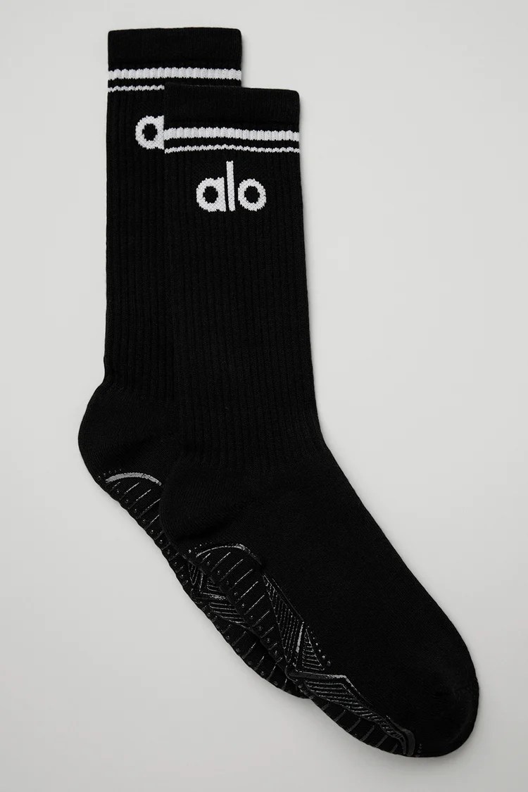 A black pair of Alo grip socks with a white stripe at the top