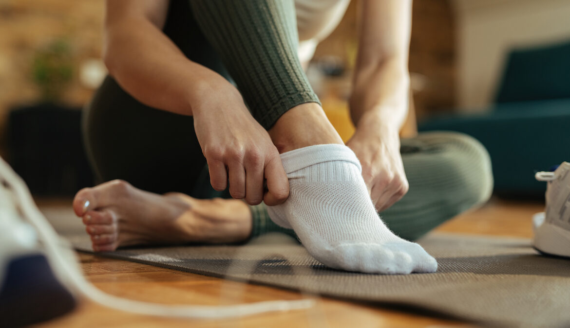 Close-up photo of woman putting on athletic grip socks.