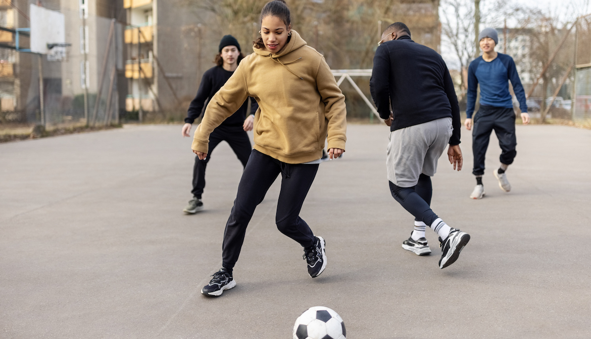 Female soccer player playing a match with friends on an urban soccer field