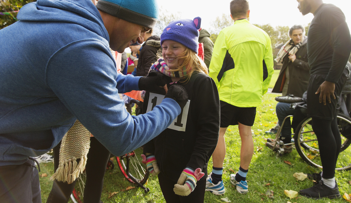 A father pinning a bib on his daughter at a turkey trot