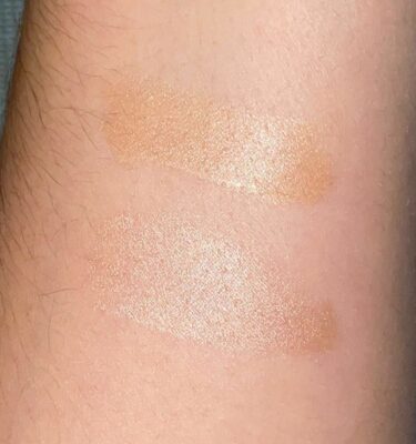 Two different shades of makeup are applied to a bare wrist. 