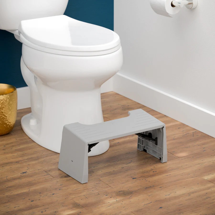 squatty potty travel porta squatty positioned in front of a toilet in a bathroom on wood floors