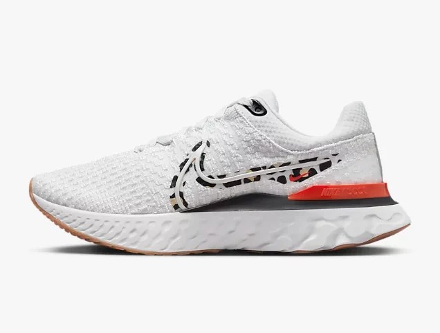 A white Nike sneaker with a cheetah print swoosh and orange stripe.