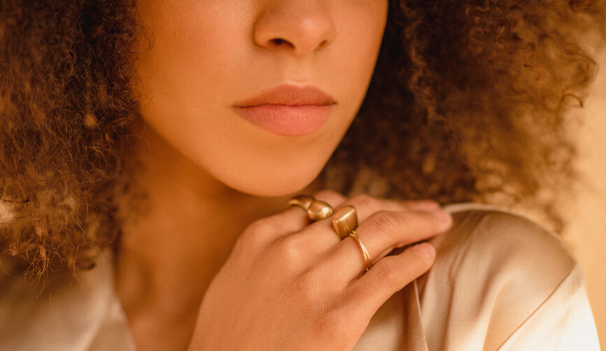 A beautiful black woman wearing gold jewelry on her hand.