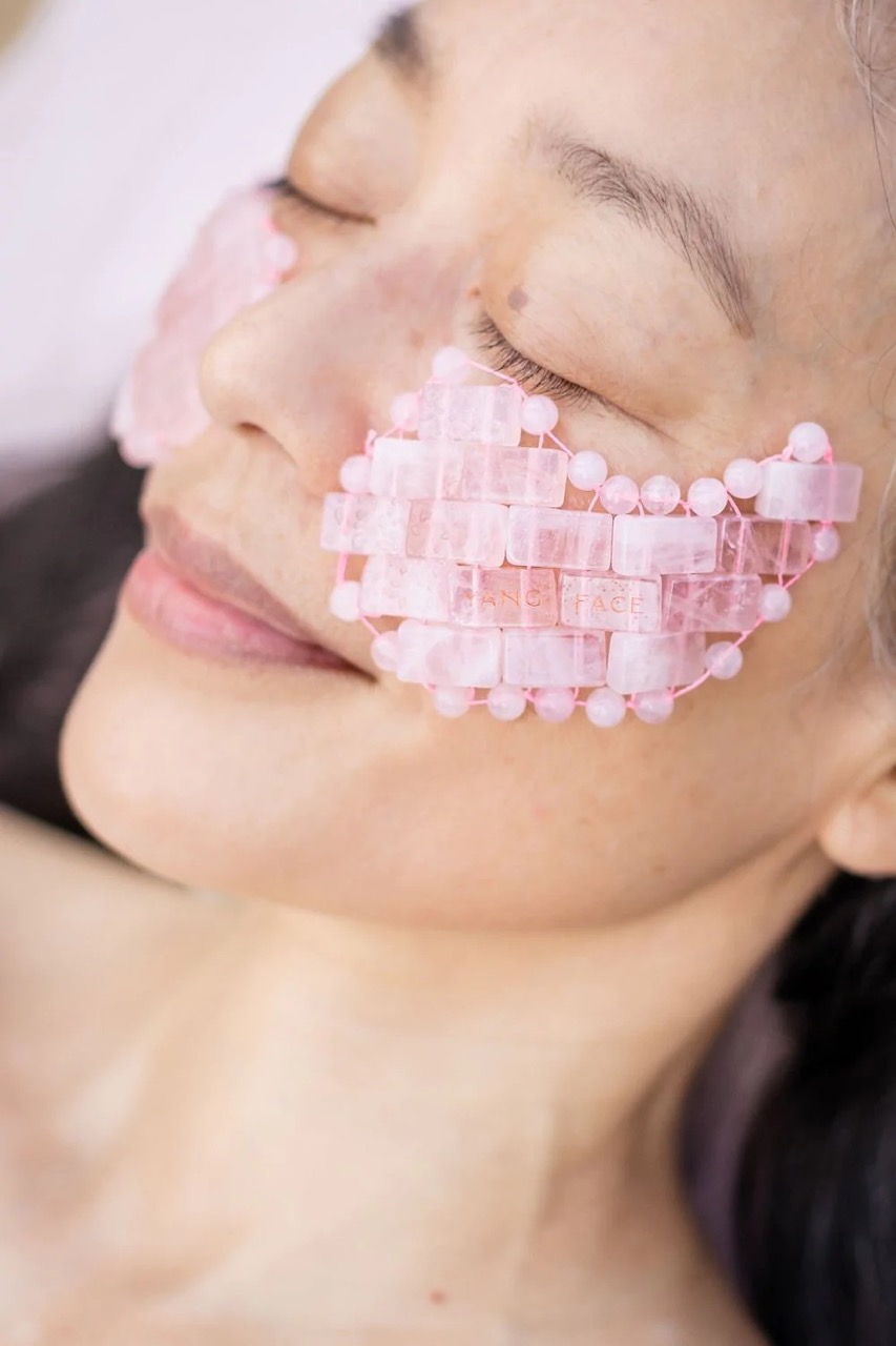 Une femme se reposant avec le masque sous les yeux Yang Face en quartz rose.