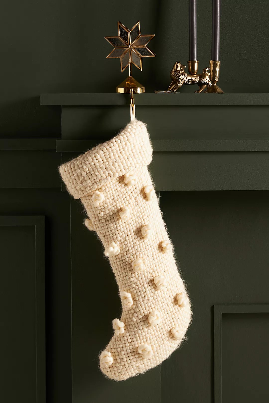 cozy bobble stocking from anthropologie black friday sale hanging on a green mantle