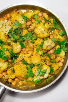 A plate of seasoned cauliflower and chickpeas, garnished with herbs.