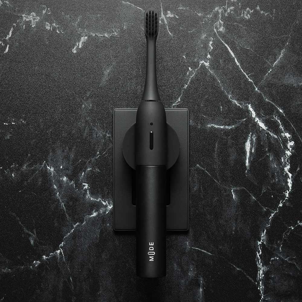 a black mode electric soft toothbrush plugged into the wall