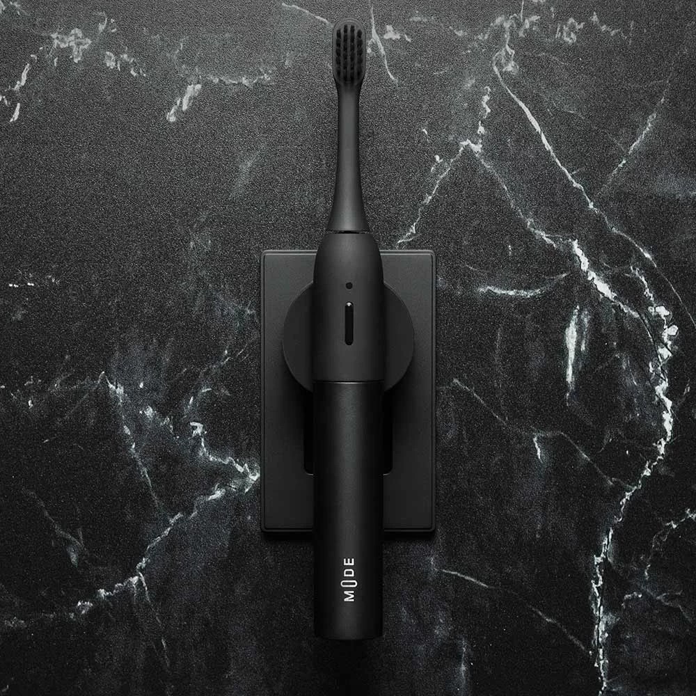 a black mode electric soft toothbrush plugged into the wall