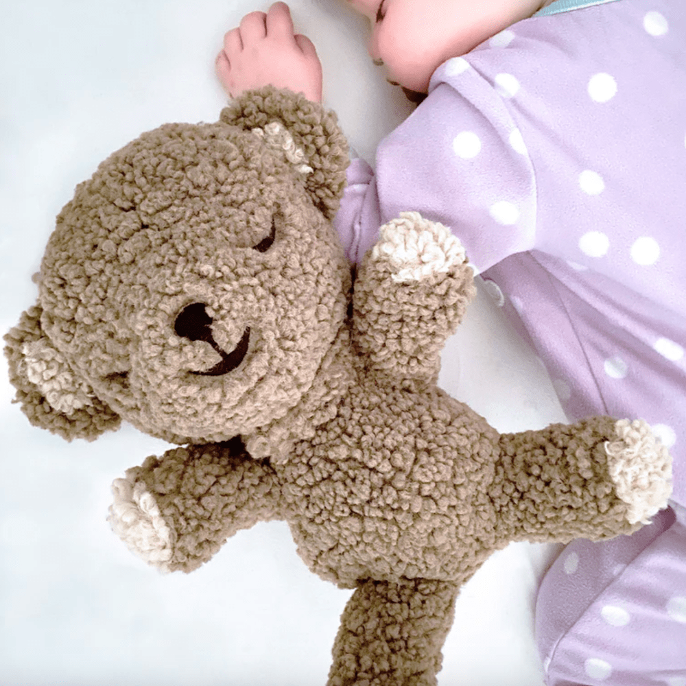 A teddy bear next to a baby