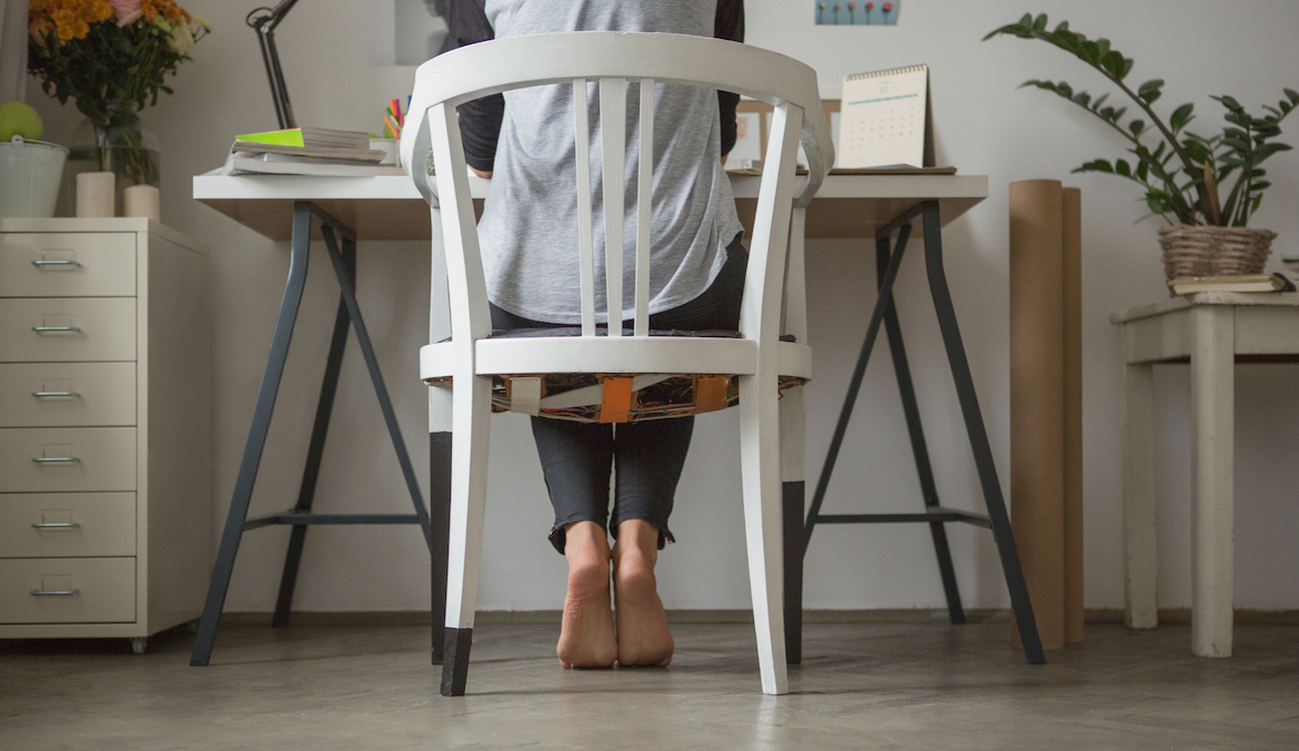 A woman sitting at a desk raising her heels in a soleus pushup position.