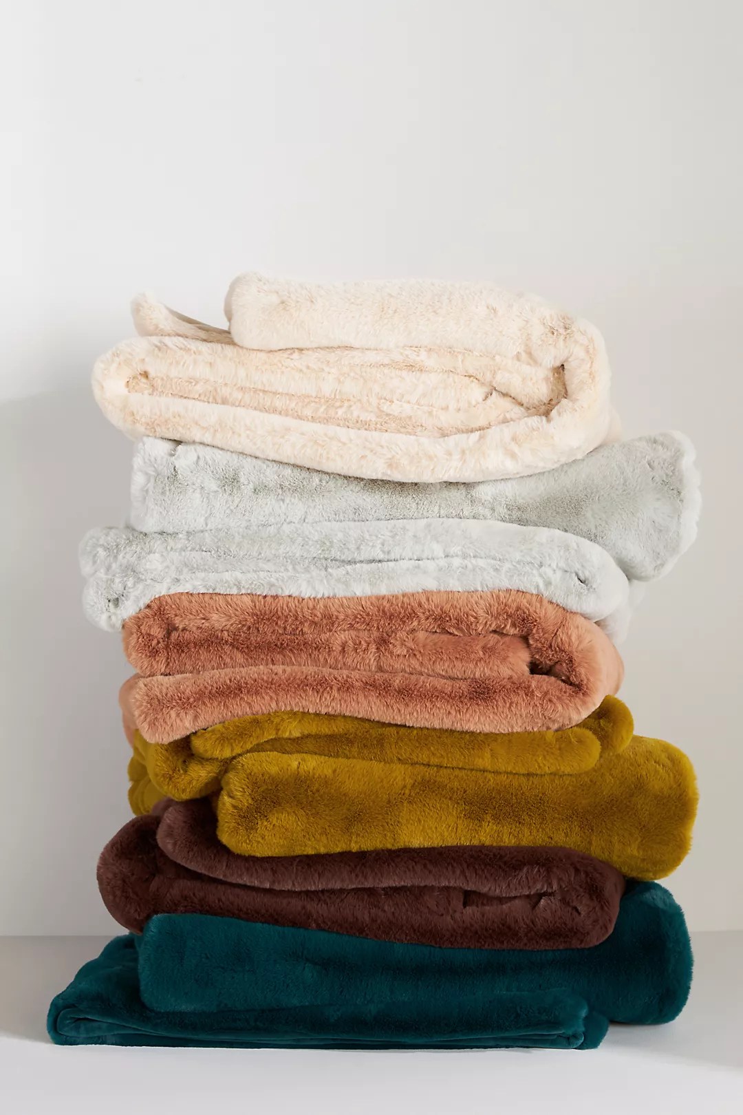 sophie faux fur blankets stacked in different colors on a white background for the anthropologie black friday sale