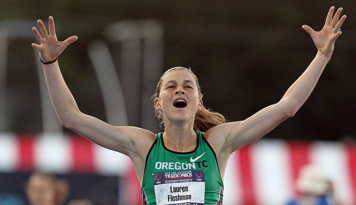 Pro runner Lauren Fleshman celebrates with her hands outstretched in the air immediately after winning a race.