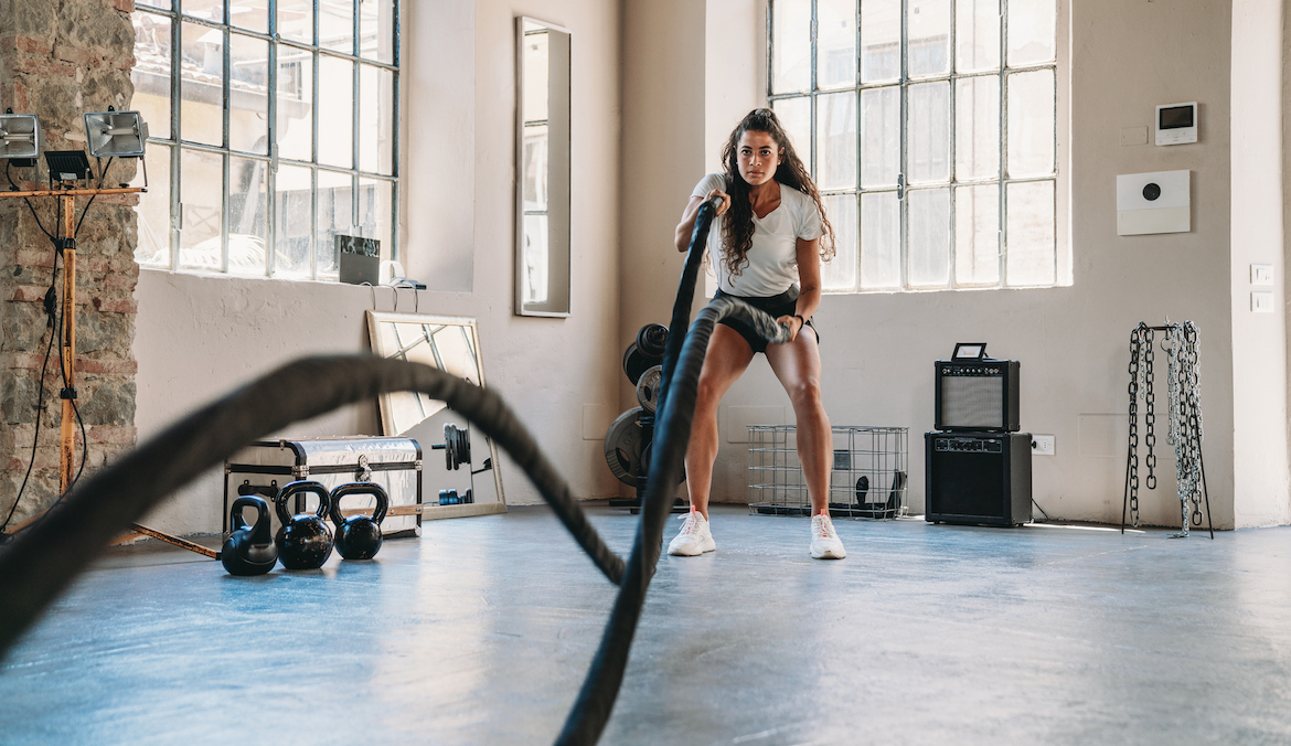 A woman doing exercises with a rope at the gym.