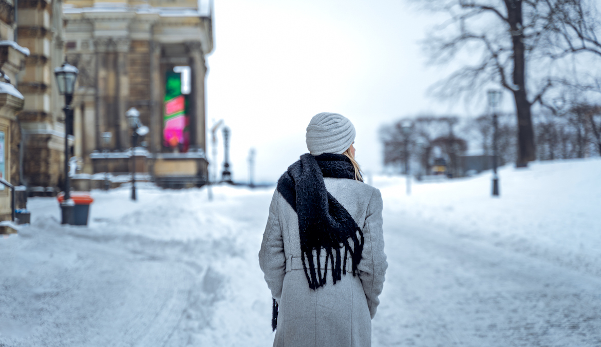 A woman walks on snowy winter street, symbolizing the zodiac effects of the winter solstice.