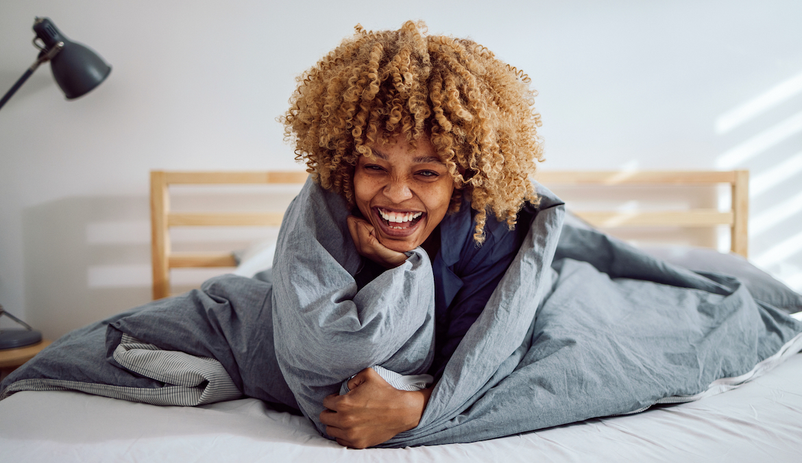 woman laughing under blanket