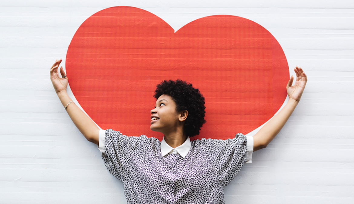 Black woman standing in front of large heart art