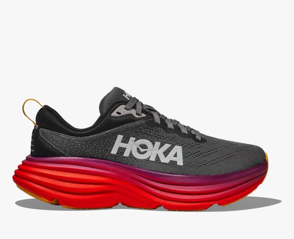 The side image of black Hoka running shoes with a ruby red sole.