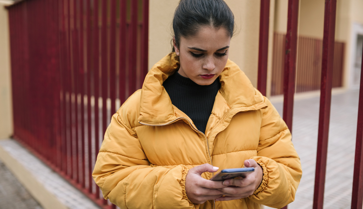 woman wearing a packable puffer jacket while on her phone