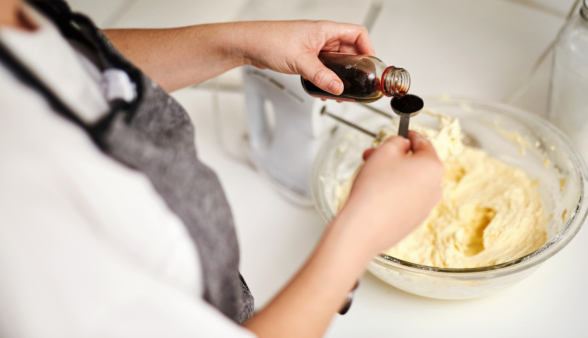 woman adding vanilla essence to her cake mixture