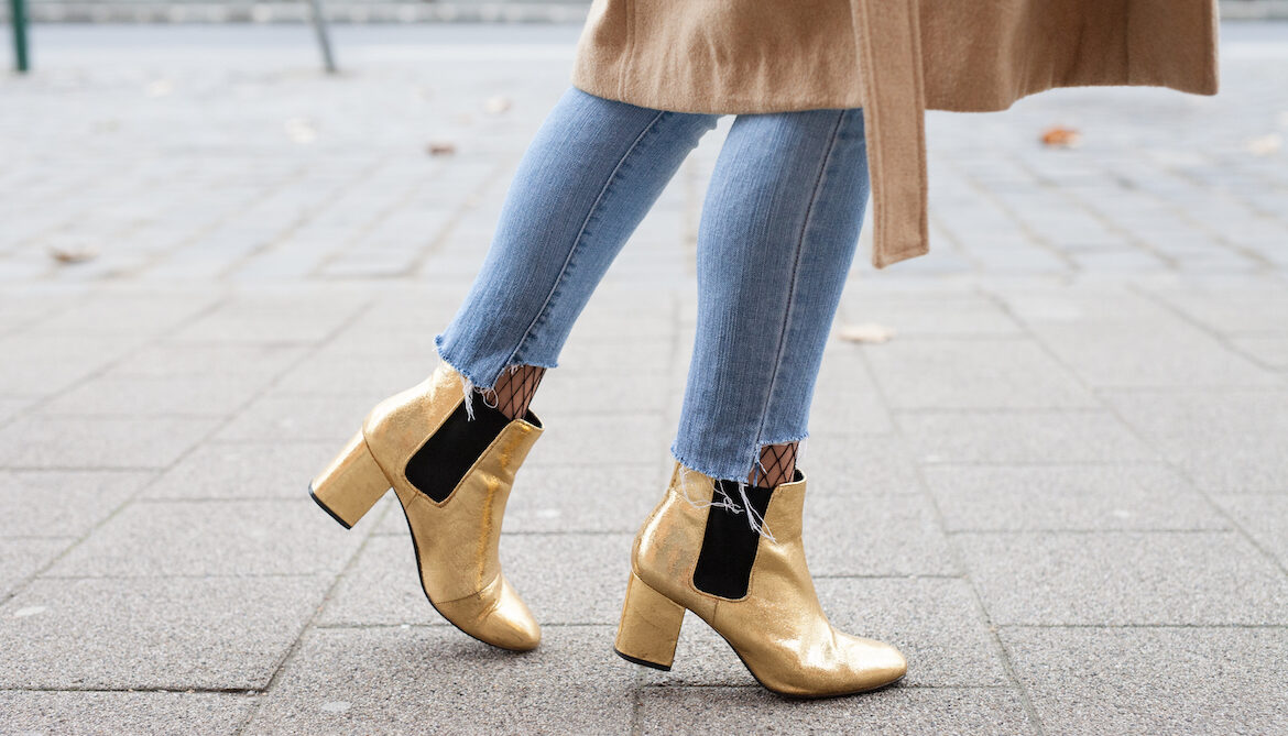 Close-up photo of a woman wearing heeled boots outside on a street.