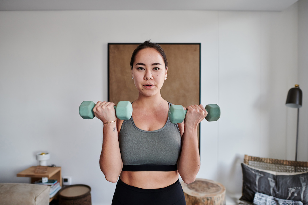Young woman working out with weights at home