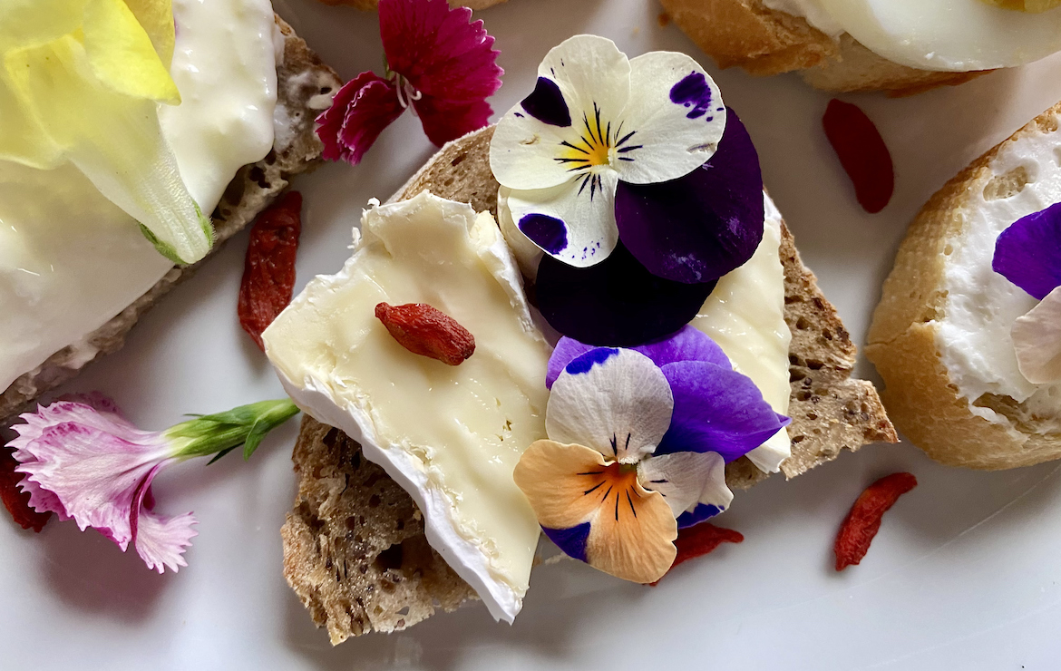 Canapés topped with cheese and edible flowers you can eat