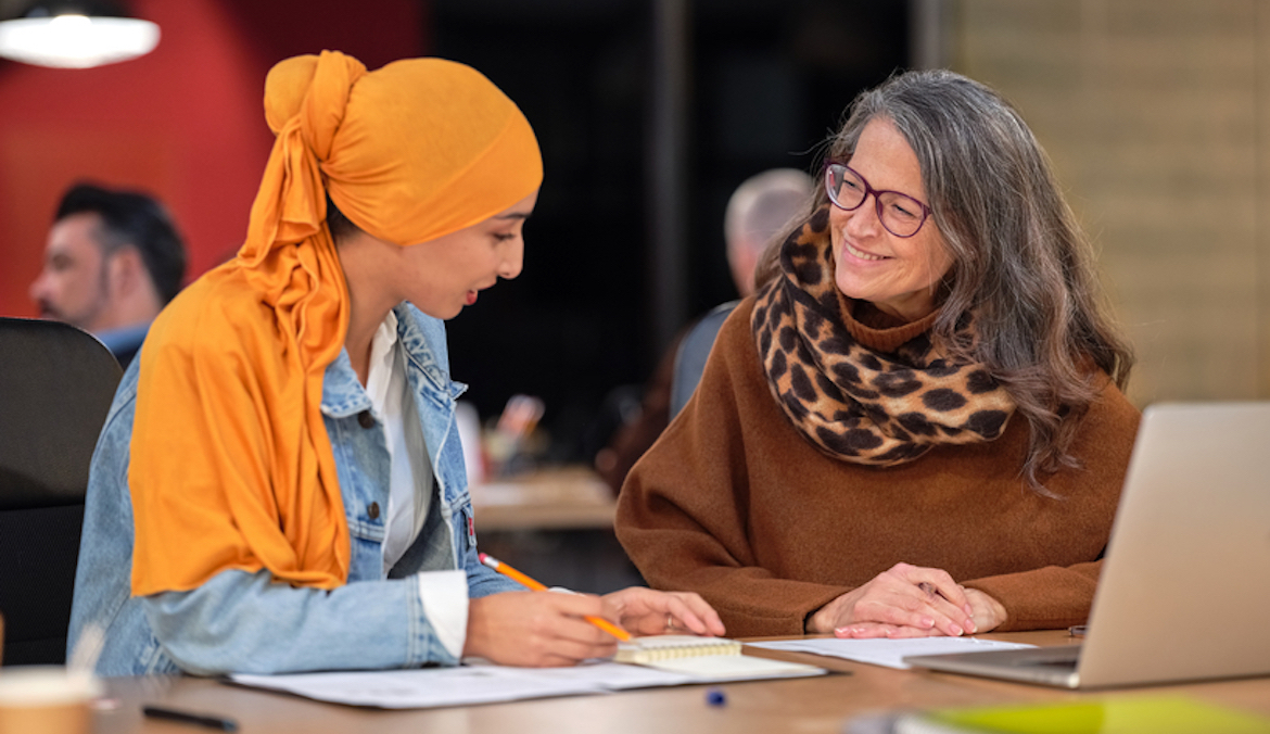 woman in hijab meeting with coworker in scarf to discuss a report at work
