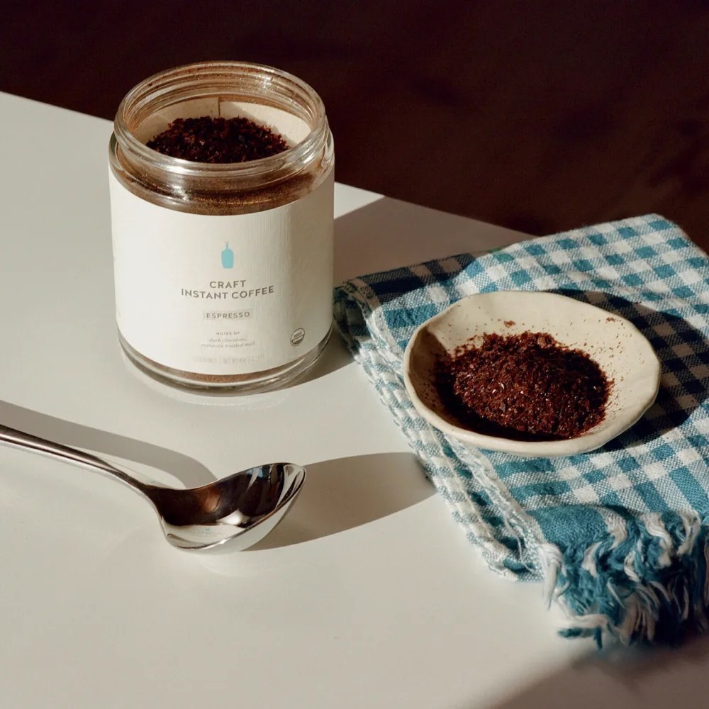 blue bottle craft instant espresso jar with a spoon and a small dish full of the instant coffee