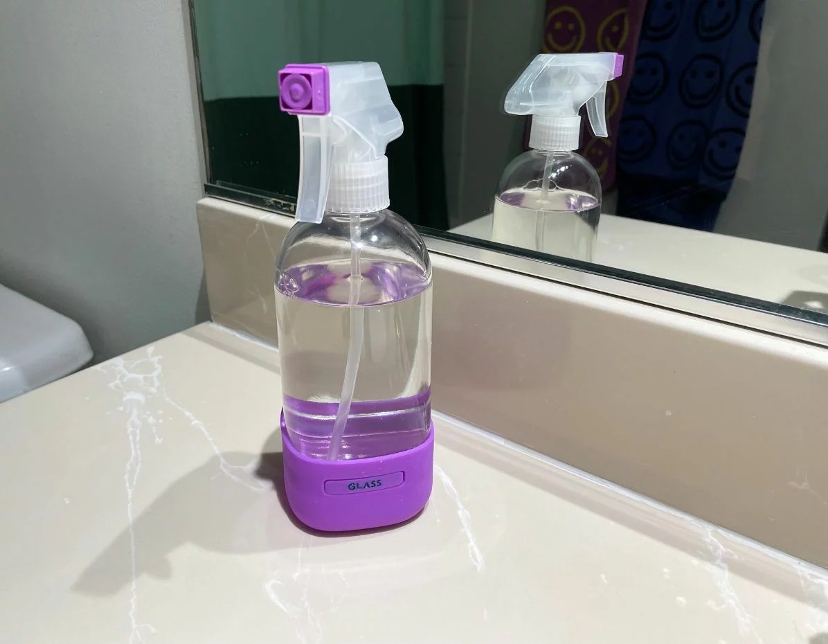 Grove Co. glass cleaner on a bathroom counter in front of a mirror