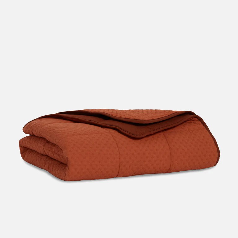 Brooklinen weighted throw blanket in terracotta on a grey background