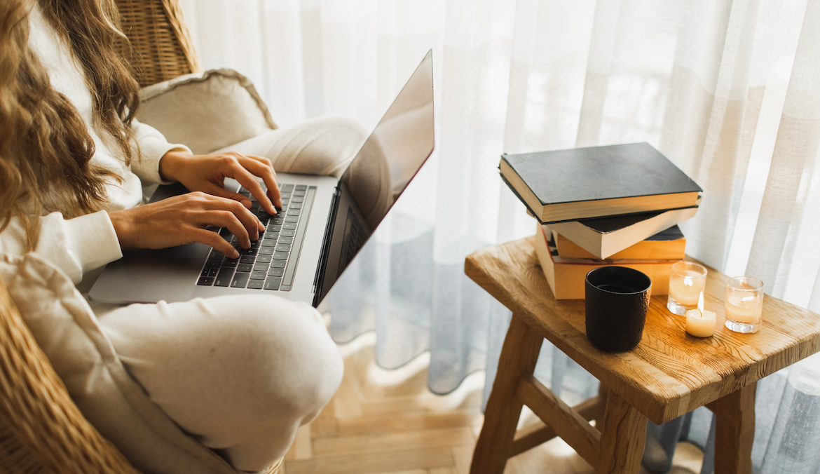 woman working from home on her laptop with a candle to support focus burning in the background