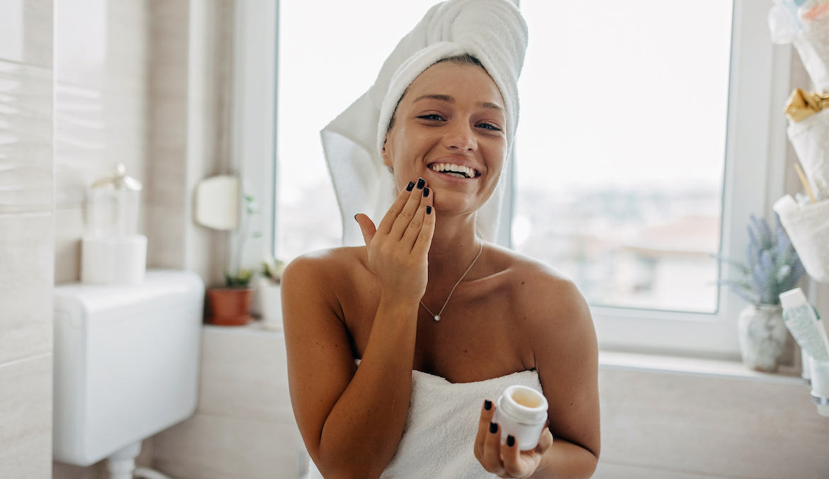 woman moisturizing her face in a bath towel