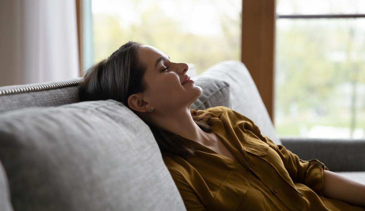 woman meditating, taking deep breaths for stress relief on couch