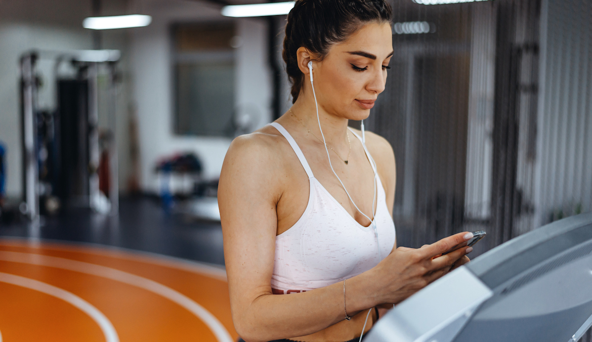 Young focused woman working out at gym jogging on a treadmill.