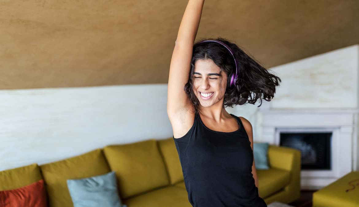 Young woman dancing with headphones on at home