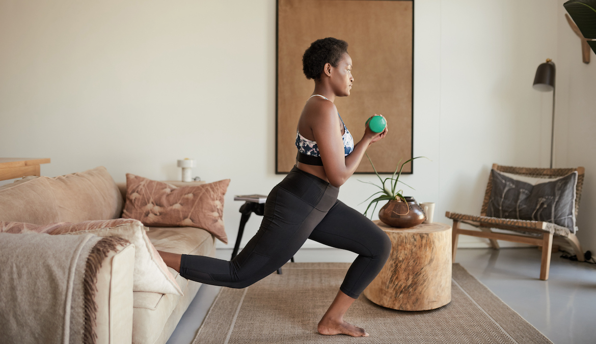 Young woman doing split squats at home on the couch