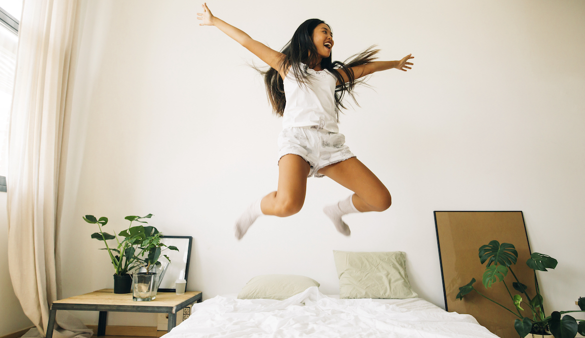 woman jumping on bed joyously