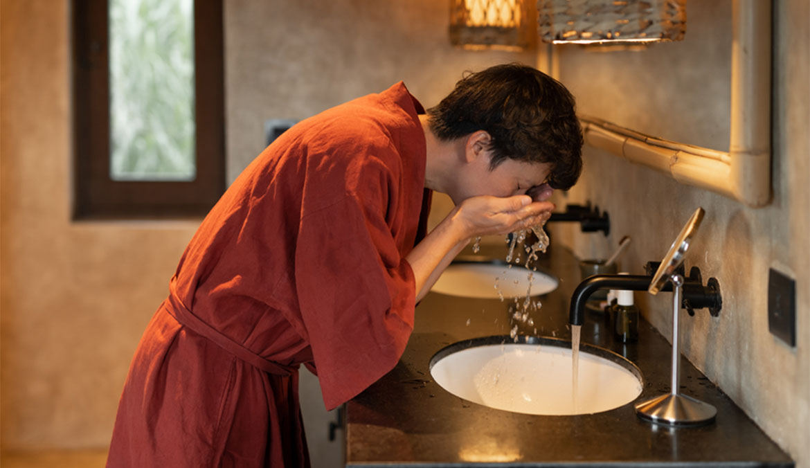 A man washing his face at the sink