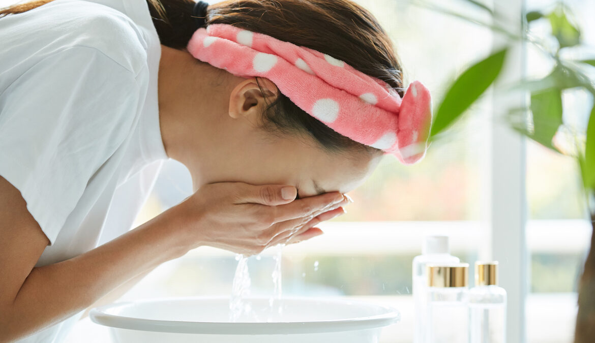 A young woman wearing a headband during her face-washing routine.