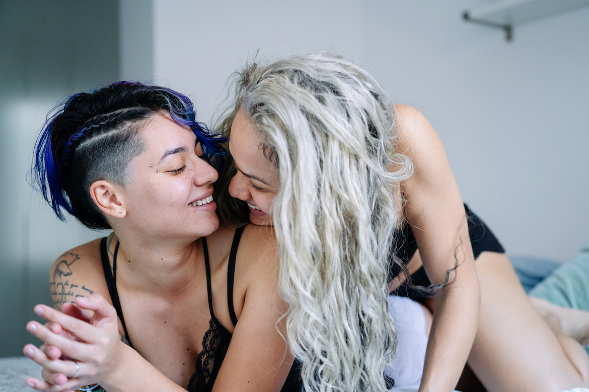 Horizontal view of gay women playful in bed with happiness.