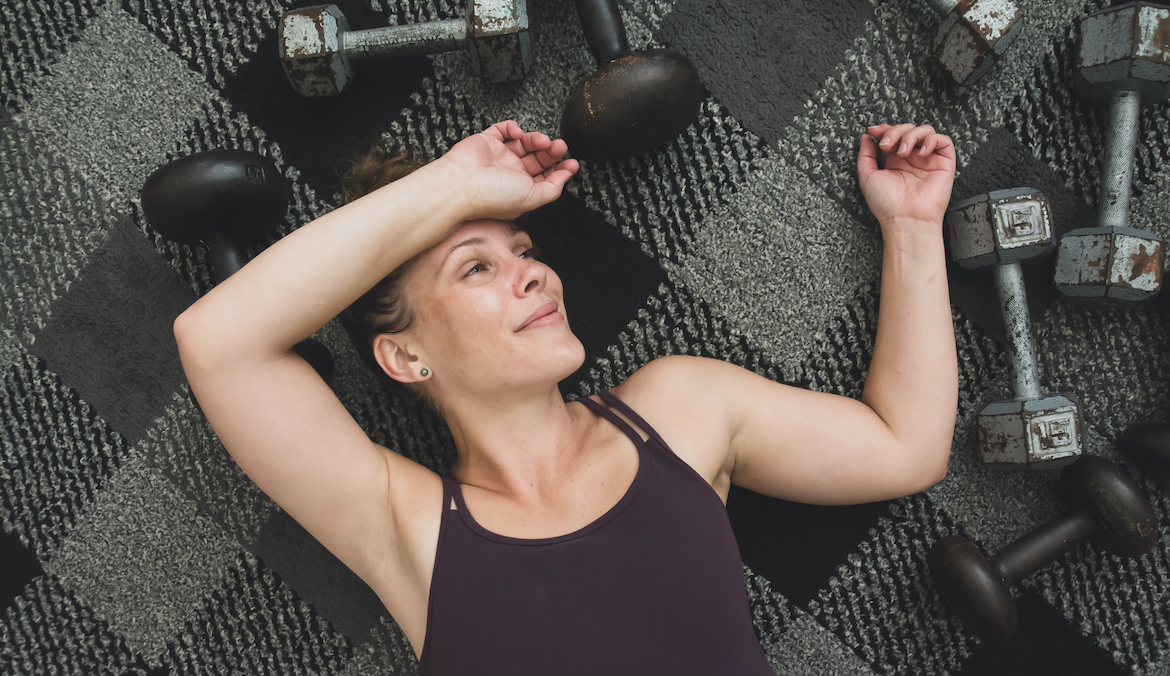 Woman with dumbbells smiling after a workout.