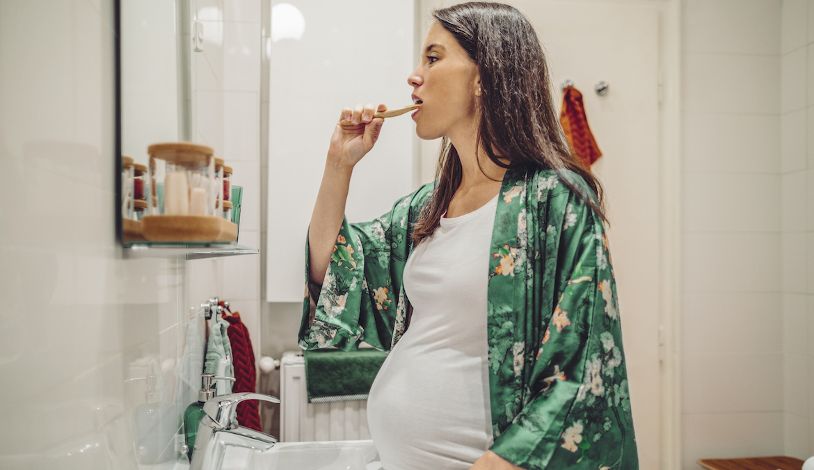 pregnant woman brushing her teeth at home