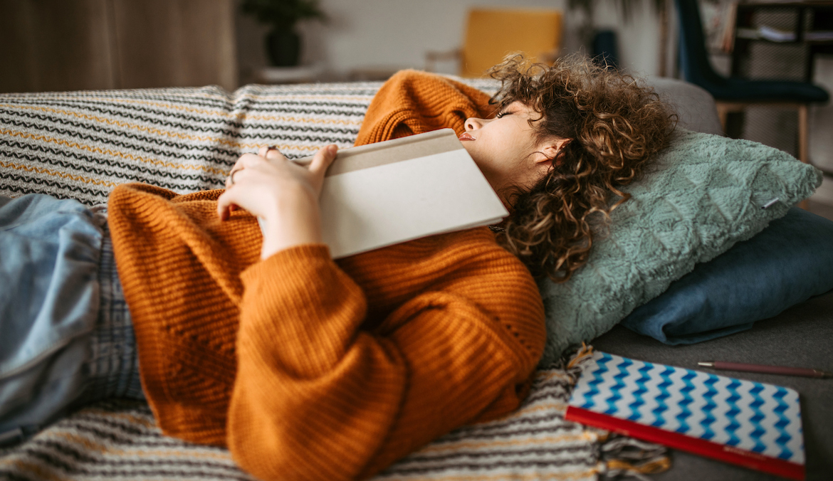 woman napping on the sofa in her living room after reading