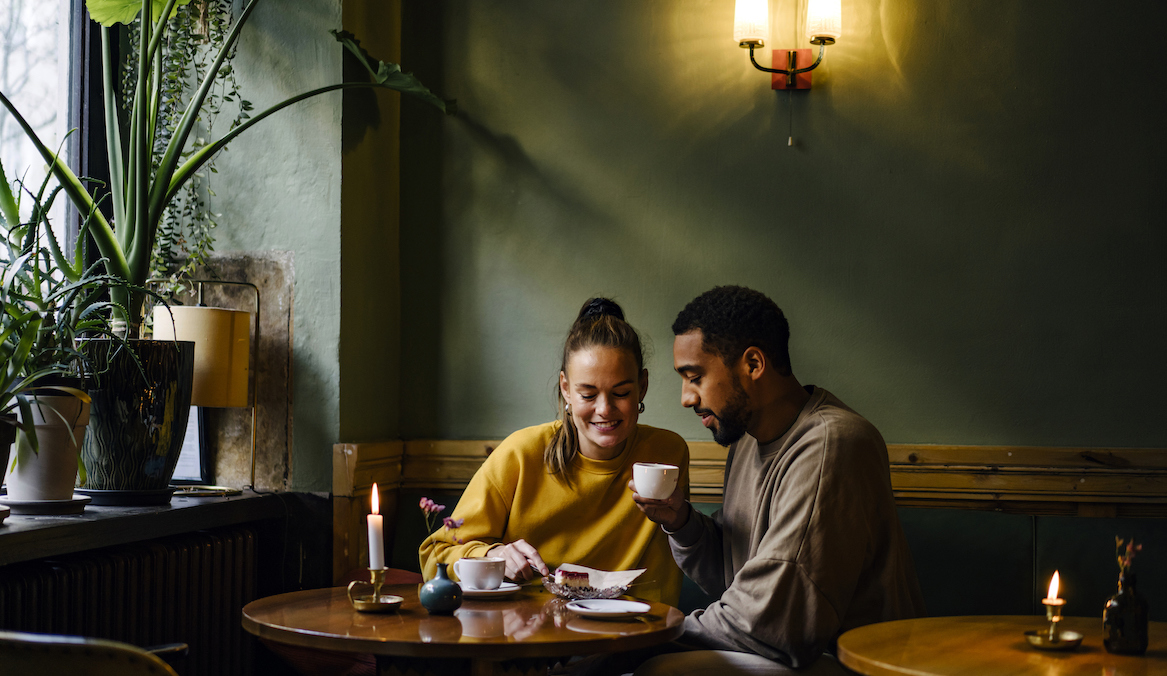 A man and a woman sit next to each other at a coffee shop while on a date.
